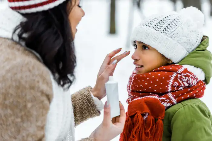 Mother Applying SPF Lotion to Daughter in Winter